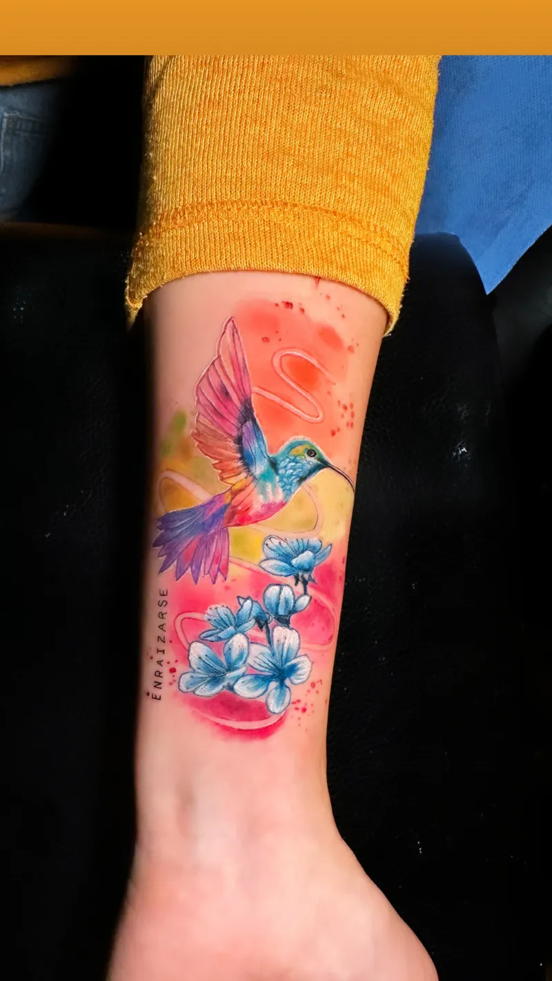 Watercolour hummingbird with blue and pink flowers on the wrist